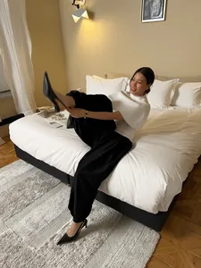Lifestyle detail of elegant black satin lantern pants worn by model in a modern bedroom