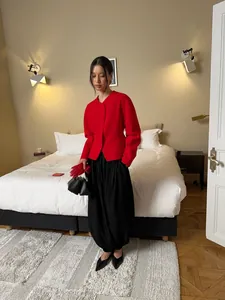 Elegant female model wearing black satin draped lantern pants in a stylish bedroom setting