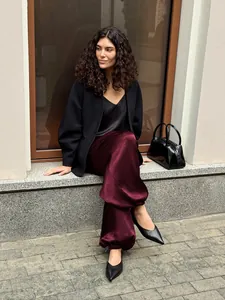 Eleganti pantaloni bordeaux in raso a gamba larga indossati da una modella in città