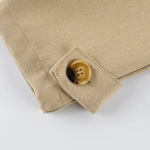 Macro close-up of a tortoiseshell button and textured khaki fabric on a trench coat sleeve.