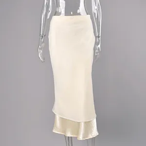 Detalle de una falda midi de satén champán con elegante capa de malla y dobladillo cola.