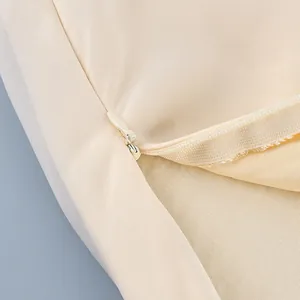 Detalle de primer plano de cremallera oculta en falda de satén beige con malla fina