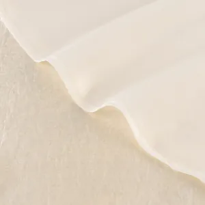 Detalle macro de la tela de malla transparente y costuras finas en una falda de satén crema