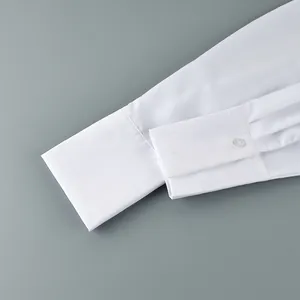Vue détaillée du poignet d'une chemise blanche à manches longues avec bouton et plis.
