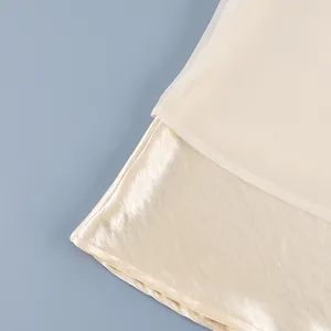 Detalle de falda midi de satén champán con dobladillo de retazos de gasa transparente
