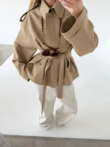 Close-up of khaki lapel trench coat with waist belt and soft texture