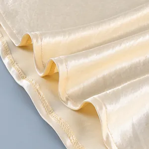 Detalle del dobladillo de la falda de satén champán con costuras finas y textura de seda suave