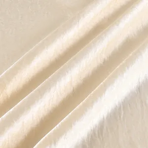 Detalle macro de tela de satén champán con textura arrugada y brillo sedoso elegante
