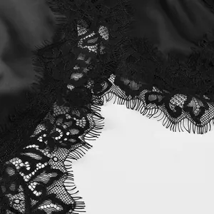 Gros plan détaillé montrant la dentelle délicate sur une robe nuisette en satin noir.