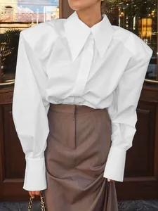 Détail d'un chemisier blanc de bureau avec un col pointu surdimensionné et épaulettes.