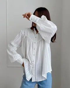 Detailed view of white French cotton blouse featuring puff sleeves and elegant pearl buttons.