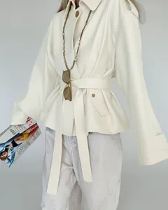 Close-up of a minimalist cream suede trench coat featuring an adjustable belted waist design