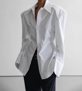 Détail d'une chemise blanche structurée à manches longues, épaules marquées et grands poignets