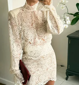 Detail of elegant white lace long-sleeve blouse and matching A-line mini skirt set