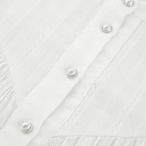 Close-up of white cotton French blouse with elegant pearl buttons and lace trim