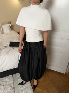 Elegant black satin lantern pants paired with white structured cape top in a bedroom setting