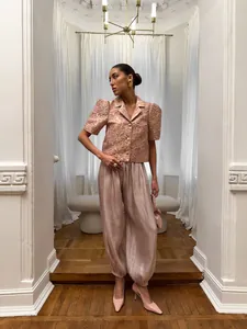 Full-length view of loose-fitting pink harem pants paired with a brocade jacket