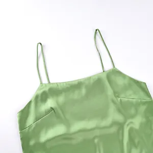 Detail shot showing the glossy satin fabric and thin straps of a green camisole top
