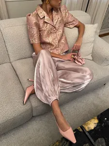 Detailed view of women's pink satin lantern pants featuring elegant high-shine texture.