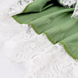 Macro shot of the delicate white floral lace trim on sage green garment fabric set
