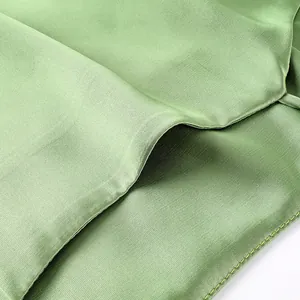 Macro detail of sage green satin fabric showing a smooth texture and fine stitching