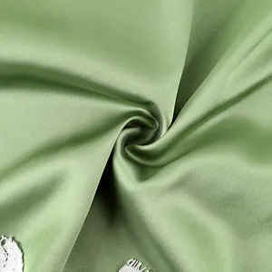 Detailed close-up showing texture of smooth sage green satin fabric with white lace