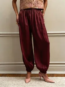 Chic burgundy satin lantern pants featuring elasticated cuffs for a relaxed fit.