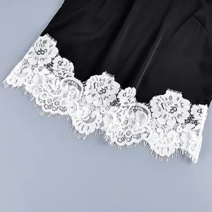 Close-up macro detail of delicate white floral lace trim on black satin pajama set hemline