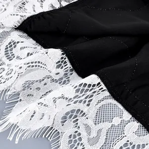Detailed macro view showing the delicate white floral lace trim on a black fabric hem