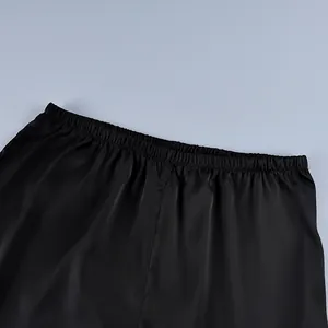 Macro detail of the elastic waistband on black silk-like satin straight trousers