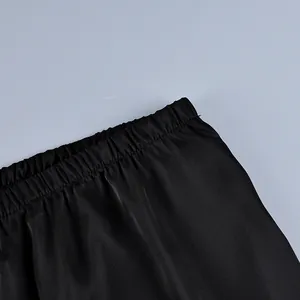 Detail view of black satin trousers featuring a comfortable elastic waistband for comfort