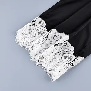 Close-up detail showing the exquisite white floral lace trim on black satin fabric