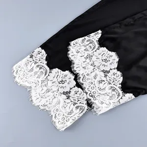 Close-up detail of delicate white floral lace trim on elegant black satin pajama pants