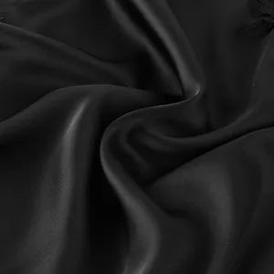 Gros plan sur un élégant tissu en satin noir avec de la dentelle délicate sur la robe