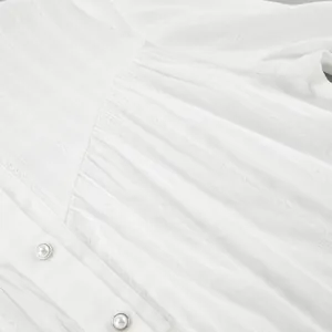 Detail view of white French cotton shirt showing textured fabric and pearl buttons