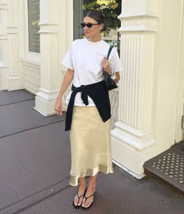 Elegante falda midi de satén champán con un panel transparente en el bajo de diseño
