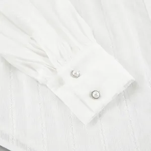 Close-up of white cotton shirt cuff with elegant pearl buttons and lace texture