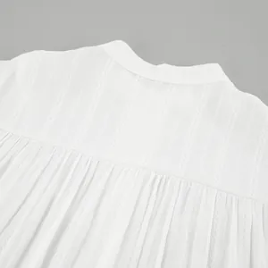 Close-up of white cotton French blouse back with intricate lace stripe texture details.