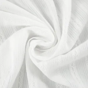 Macro close-up detail of white pure cotton fabric featuring delicate lace-like embroidery