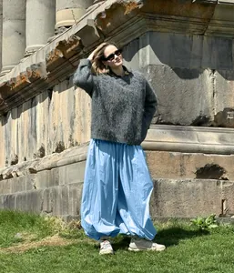 Fashionable women's light blue wide-leg balloon harem pants styled in a scenic outdoor setting