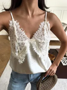 Close-up detail of a white lace V-neck camisole top featuring elegant satin fabric.
