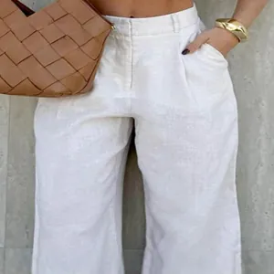 Close-up detail of white linen high-waisted wide-leg trousers showing fabric texture