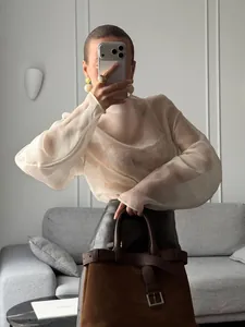 Vista detallada de una elegante blusa de malla transparente marfil usada por una modelo