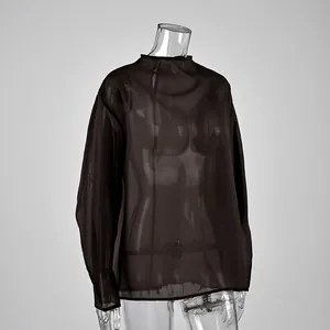 Detalle lateral de un top negro de manga larga en malla transparente sobre un maniquí.