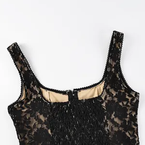 Close-up detail of black floral lace tank top with beige lining and scalloped edges