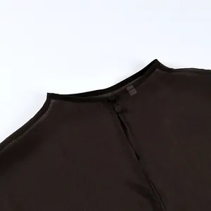 Detalle de primer plano de un top de malla negra transparente con cierre de botón elegante.