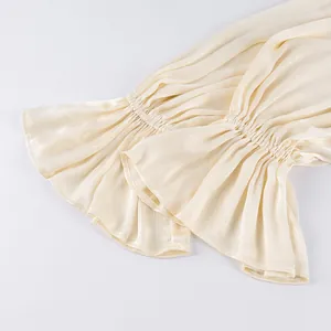 Detailopname van geplooide ruches manchetten op een elegante crèmekleurige Franse broek