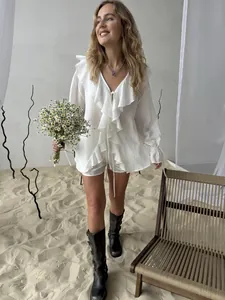 Detailansicht des eleganten weißen Rüschenoberteils und der passenden Shorts am Modell