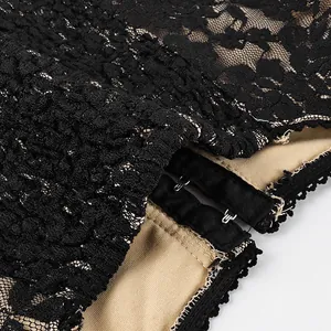 Macro detail of black floral lace fabric with hook-and-eye closure and beige lining.
