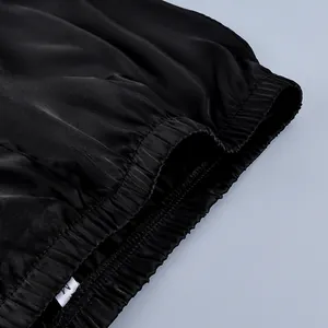 Close-up view of the elastic waistband on high-quality black satin straight pants.